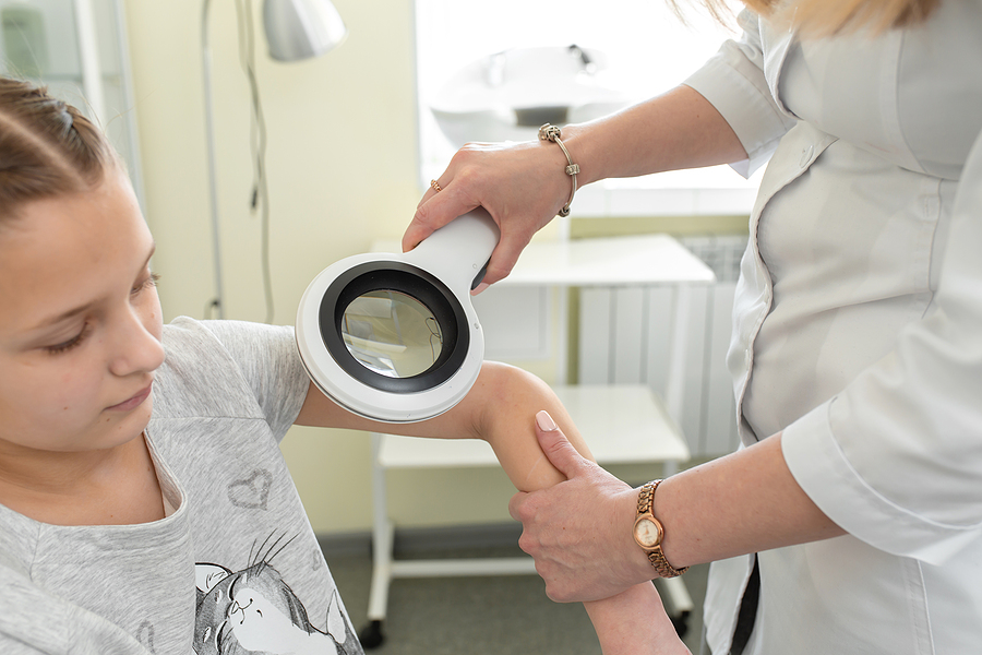 Paediatric dermatologist in Melbourne examines a girl with a dermatoscope.