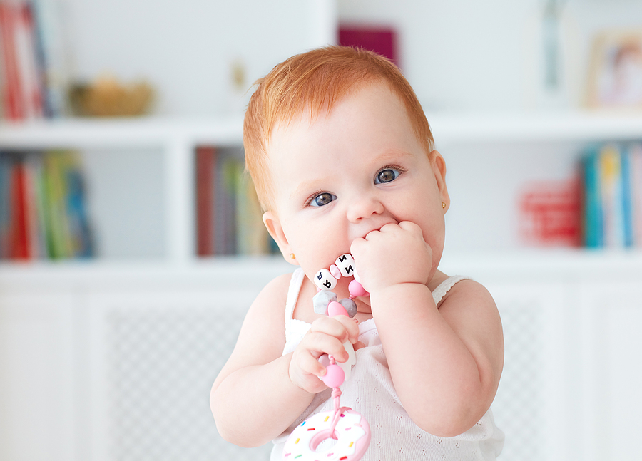 Infant baby girl biting a silicone teether made in Australia